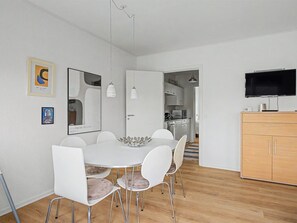 A modern kitchen with a flat-screen TV, a dining area with a white table and chairs, and a wooden cabinet. - "Leefke" - 200m from the sea by Interhome (Rudkøbing)