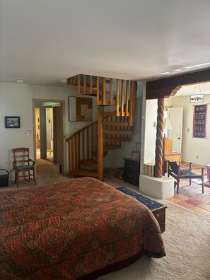 Ein Schlafzimmer mit einem großen Bett, einer Holztreppe, einem Stuhl und einer Kommode.