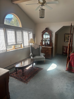 Une pièce dotée d’un ventilateur de plafond, d’un grand miroir, d’une chaise, d’une table et d’un tapis à motifs.