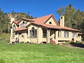 Ein zweistöckiges Haus mit rotem Ziegeldach, Schornstein und einer großen Veranda.