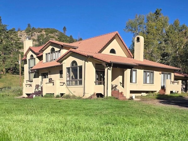Ein zweistöckiges Haus mit rotem Ziegeldach, Schornstein und einer großen Veranda.