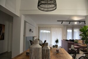Un salon moderne avec une table à manger en bois, un canapé et une grande plante.