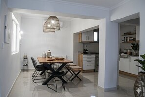 A modern kitchen with white cabinets, a wooden dining table, and black chairs. - OCEANIVES LUXURY VILA IN PALIO KAVALA ME KΗΠΟ (KAVALA)