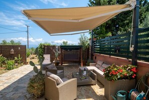 An outdoor patio area with wicker furniture, a table, and a canopy. - OCEANIVES LUXURY VILA IN PALIO KAVALA ME KΗΠΟ (KAVALA)