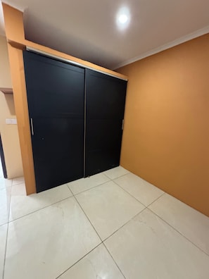 A room with a tiled floor, a black wardrobe, and a brown wall. - ZEMMA Apartments Unit 3 (Willemstad)