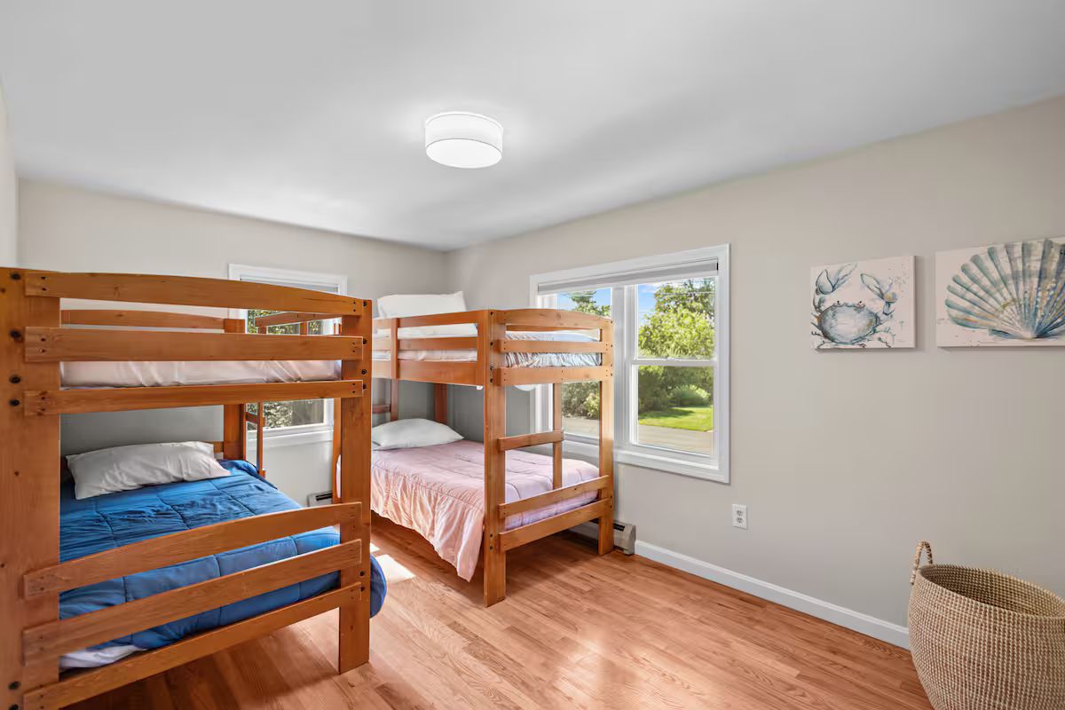 Ein Zimmer mit Etagenbetten, einem großen Fenster und Bildern an der Wand.