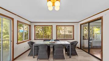 A dining area with a table and chairs, large windows, and a view of the outdoors.