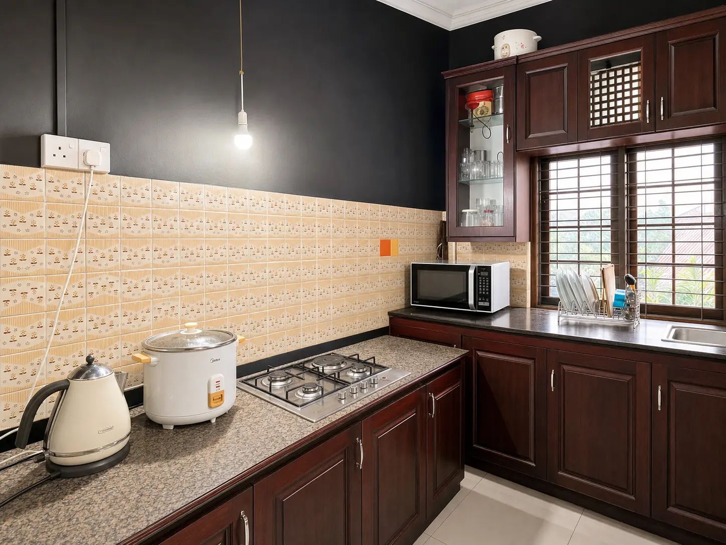 A kitchen with a gas stove, a kettle, a microwave, and a window with blinds.