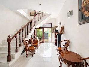 Una escalera con barandillas de madera que lleva a un rellano con una mesa y sillas.