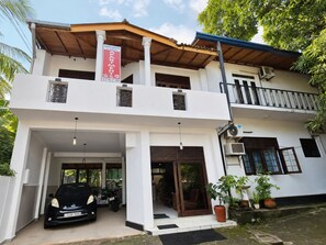 A two-story building with a sign for 'Sahinda Tourist Inn' and a car parked in the entrance.