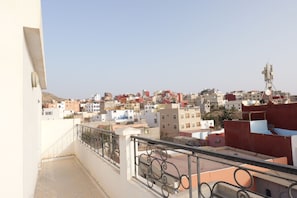 A balcony with a metal railing overlooking a densely packed urban area with various buildings. - Authentic Apartment in Tamraght – A Peaceful Stay Near the Beach (Tamraght)