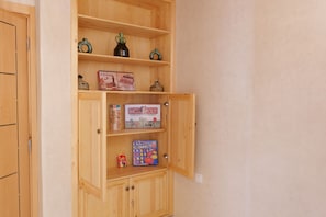 A wooden cabinet with multiple shelves containing board games. - Authentic Apartment in Tamraght – A Peaceful Stay Near the Beach (Tamraght)
