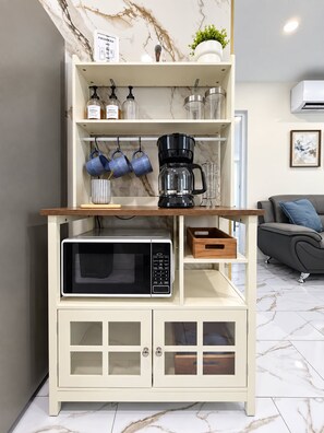 A kitchen area with a built-in microwave, coffee maker, and storage cabinets. - Stylish 3BR Near SJU Airport Sleeps 6 (Carolina)