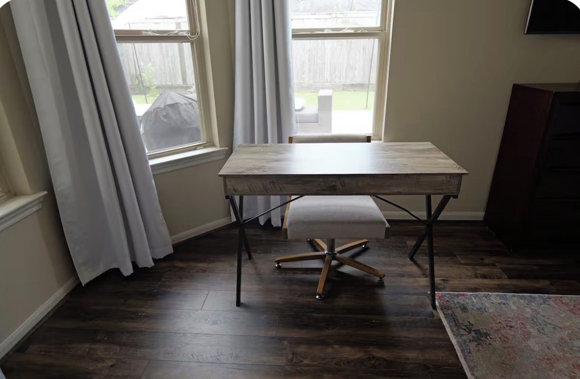 Una habitación con una mesa de madera, un banco y una ventana con cortinas.