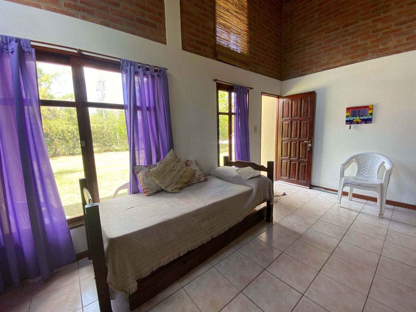 A room with a bed, a chair, and a door leading outside.