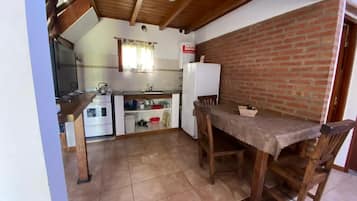 A kitchen with a brick wall, wooden ceiling, and a dining area with a table and chairs.