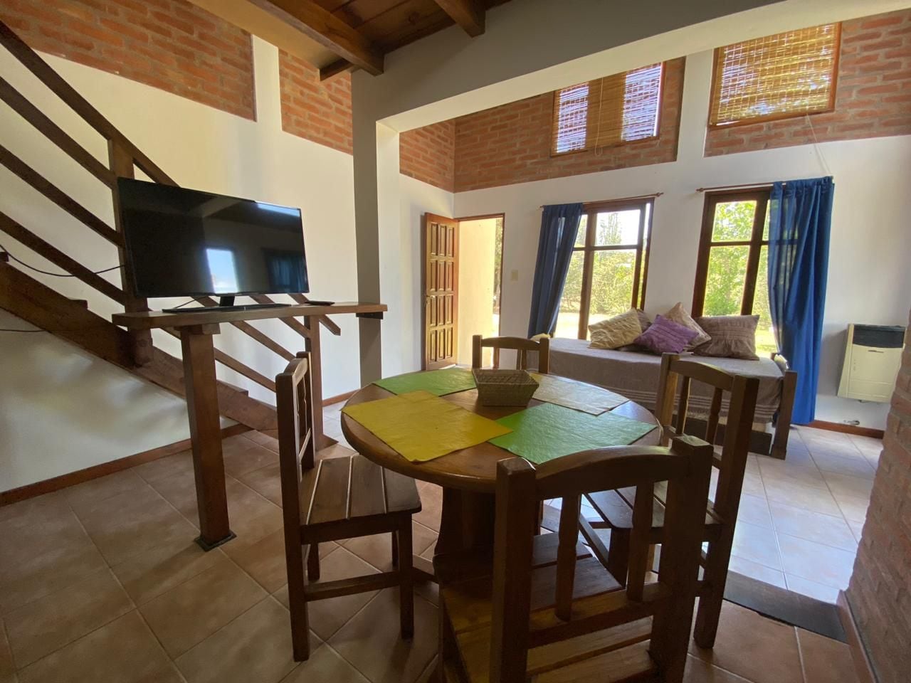 A dining area with a round table, chairs, and a television.