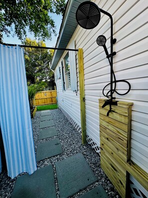 Un chemin menant à une maison entourée d’une clôture en bois et agrémentée d’un lampadaire métallique de jardin.