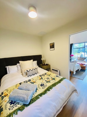 A neatly made bed with a floral-patterned blanket and pillows, a bedside table with a lamp, and a framed picture on the wall. - Lady Geraldine’s Guesthouse | Sleeps 2 Boutique (Geraldine)