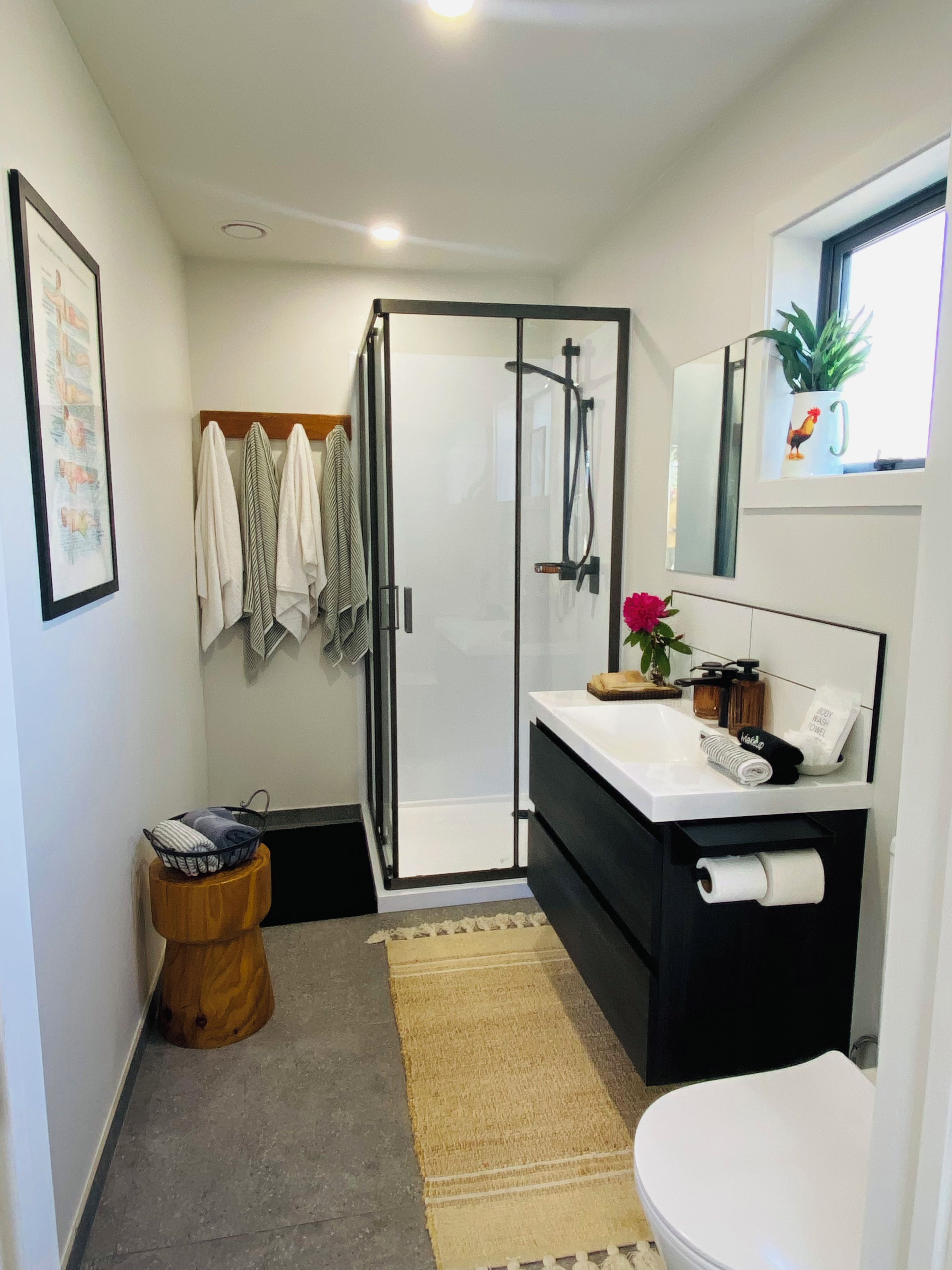 A modern bathroom with a glass shower enclosure, a white sink with a mirror above, and a toilet.