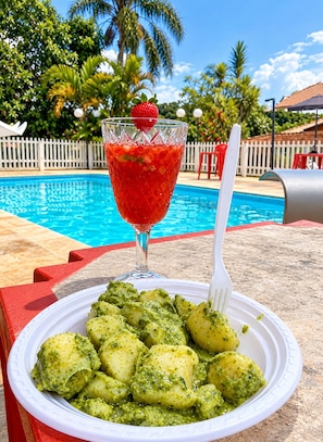 Un cadre agréable au bord de la piscine, avec un verre à la main et un bol de nourriture à proximité.