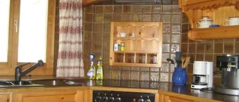 A kitchen with wooden cabinets, a built-in shelf, a coffee maker, and a dishwasher.