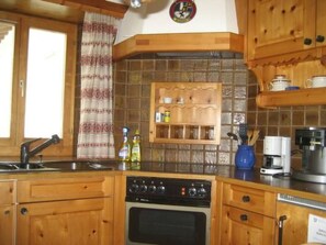 A kitchen with wooden cabinets, a built-in shelf, a coffee maker, and a dishwasher. - Haus alte Post, (Samnaun-Compatsch) by Interhome (Samnaun)