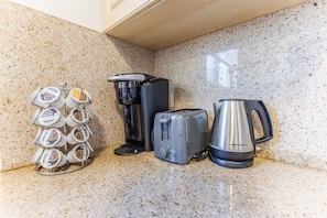 Uma bancada de cozinha com cafeteira, torradeira e chaleira.