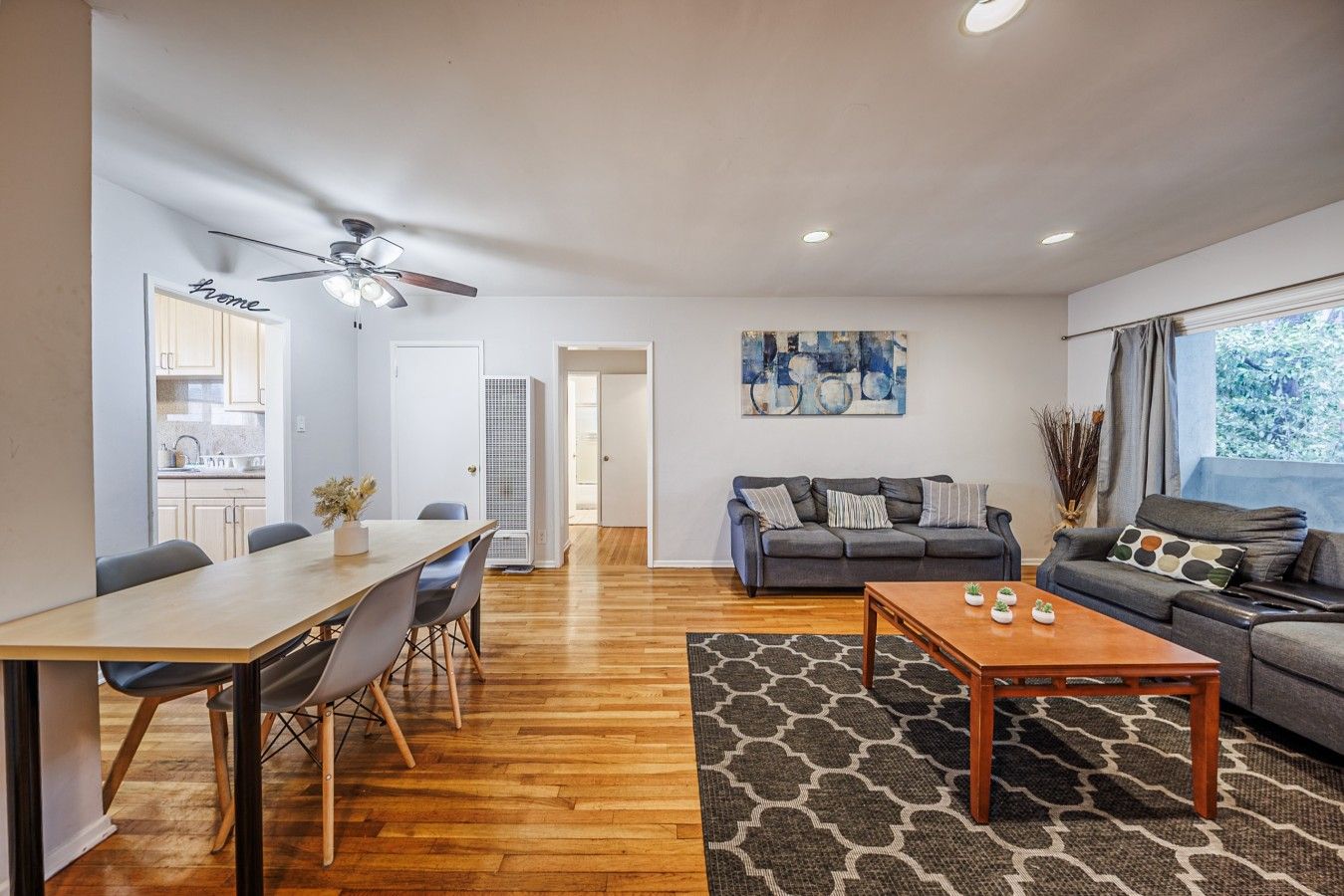 A modern living room with a sofa, coffee table, and dining area with chairs and a table.