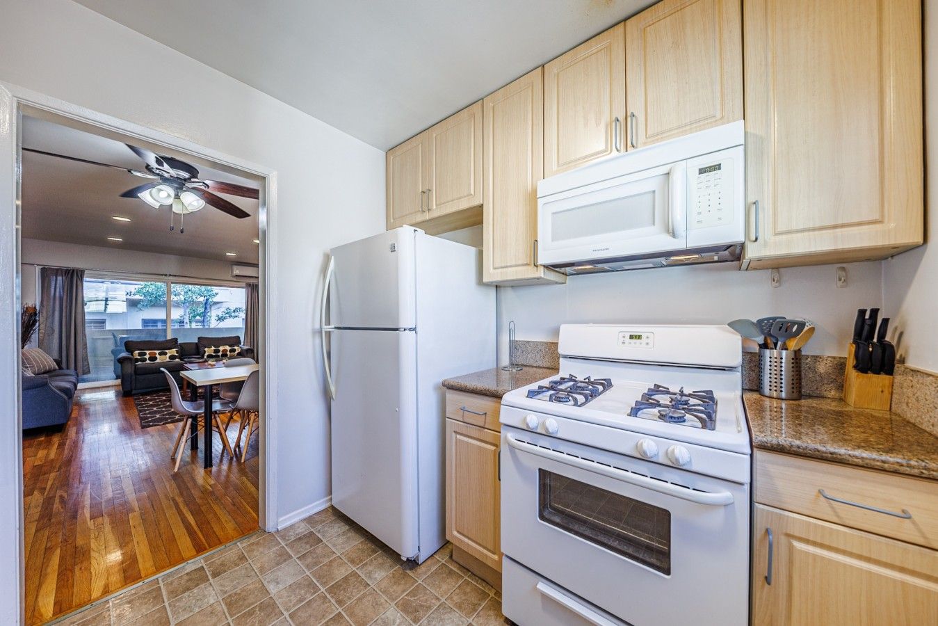 Una cocina compacta con refrigerador, estufa, microondas y armarios de madera.