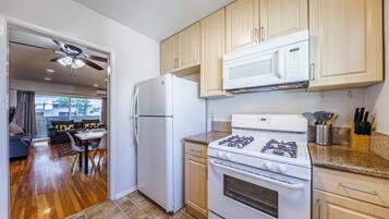 Una cocina compacta con refrigerador, estufa, microondas y armarios de madera.