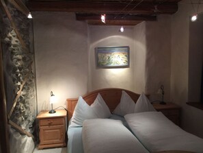 A bedroom with a wooden headboard, a single bed with white bedding, a nightstand with a lamp, and a painting on the wall. - Haus alte Post, (Samnaun-Compatsch) by Interhome (Samnaun)