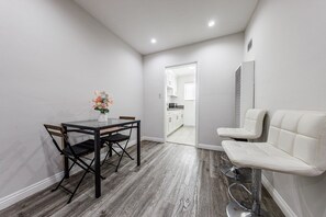 A modern room with a dining table, chairs, a sofa, and a kitchen in the background. - Beverly Hills 1BR Sleeps 4, Parking, Near Cedars (Beverly Hills)