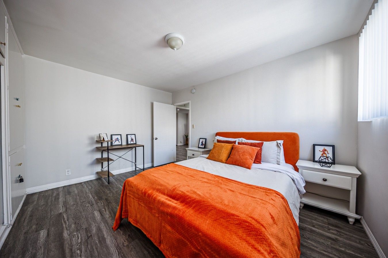 Un dormitorio con cama, mesita de noche, escritorio y puerta.