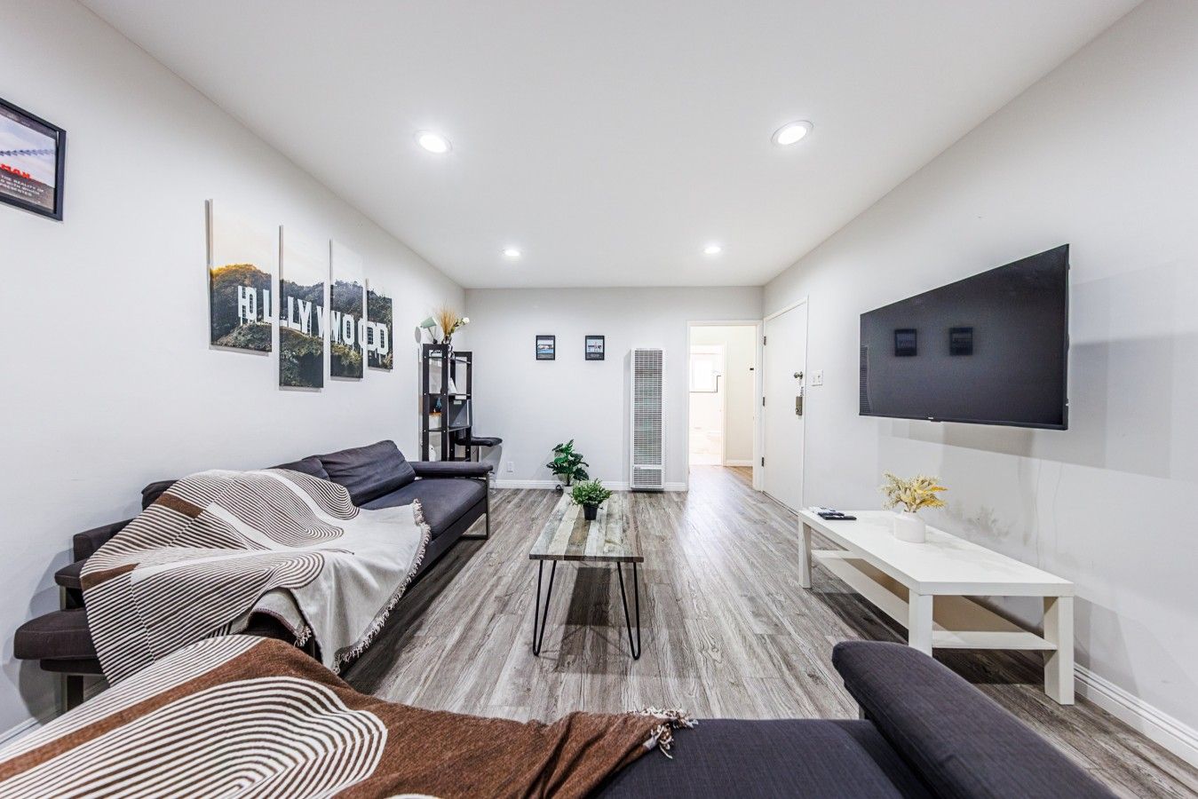 Una sala de estar moderna con un sofá, una mesa de centro y un televisor montado en la pared.