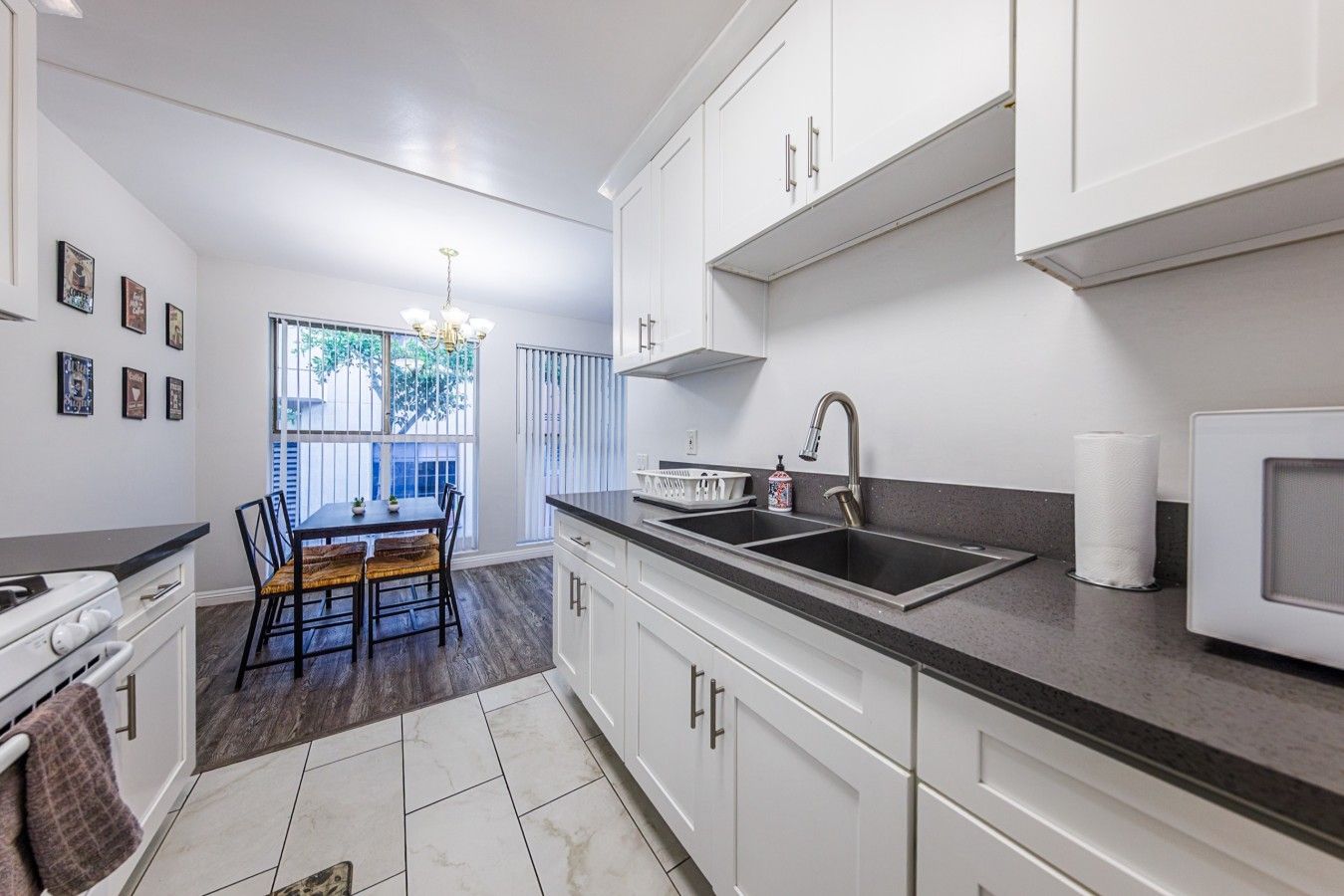 Uma cozinha moderna com armários brancos, bancada preta e um espaço de jantar com mesa e cadeiras.