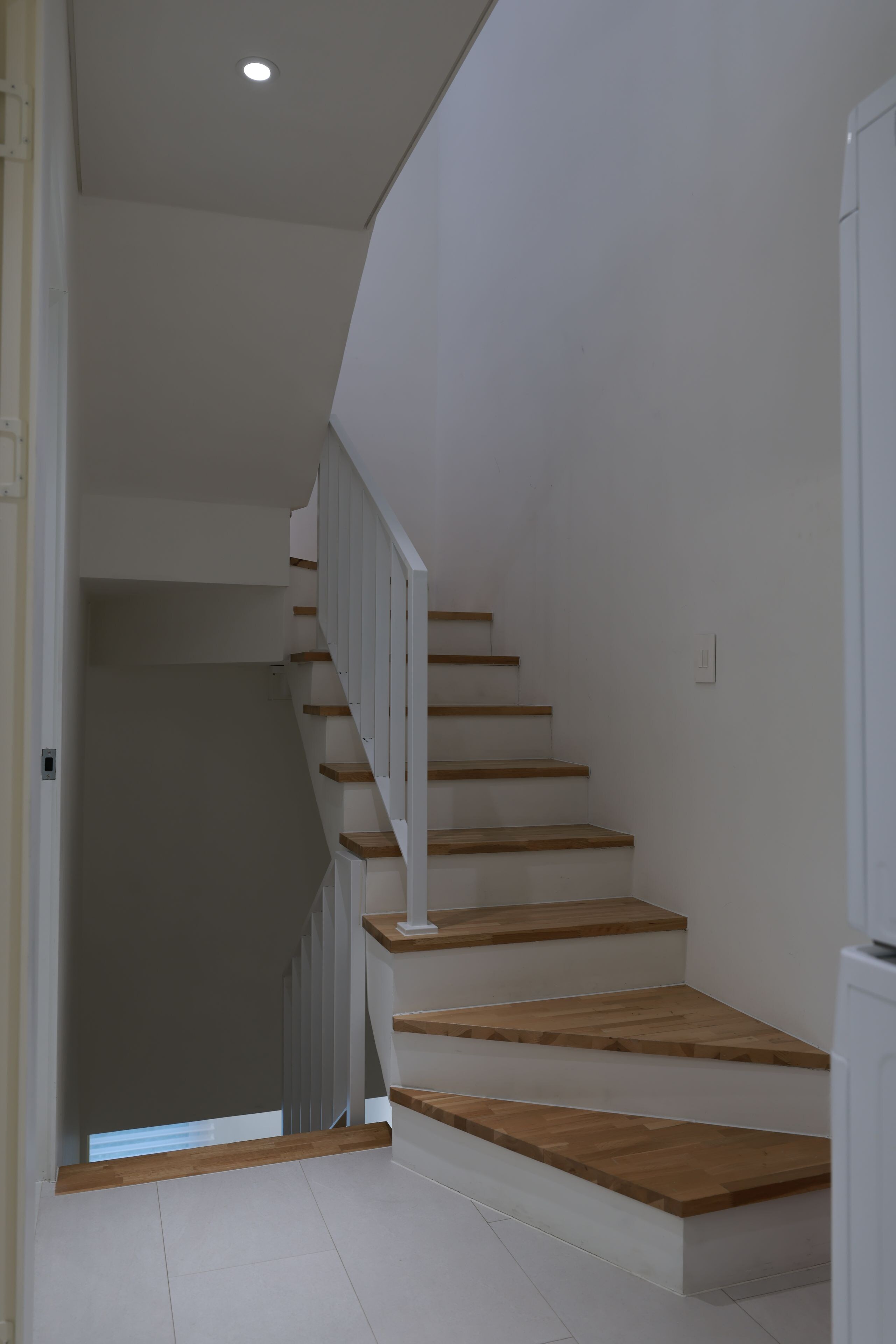 Una escalera con escalones de madera y paredes blancas.