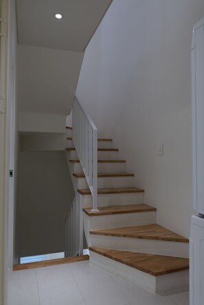 Una escalera con escalones de madera y paredes blancas.