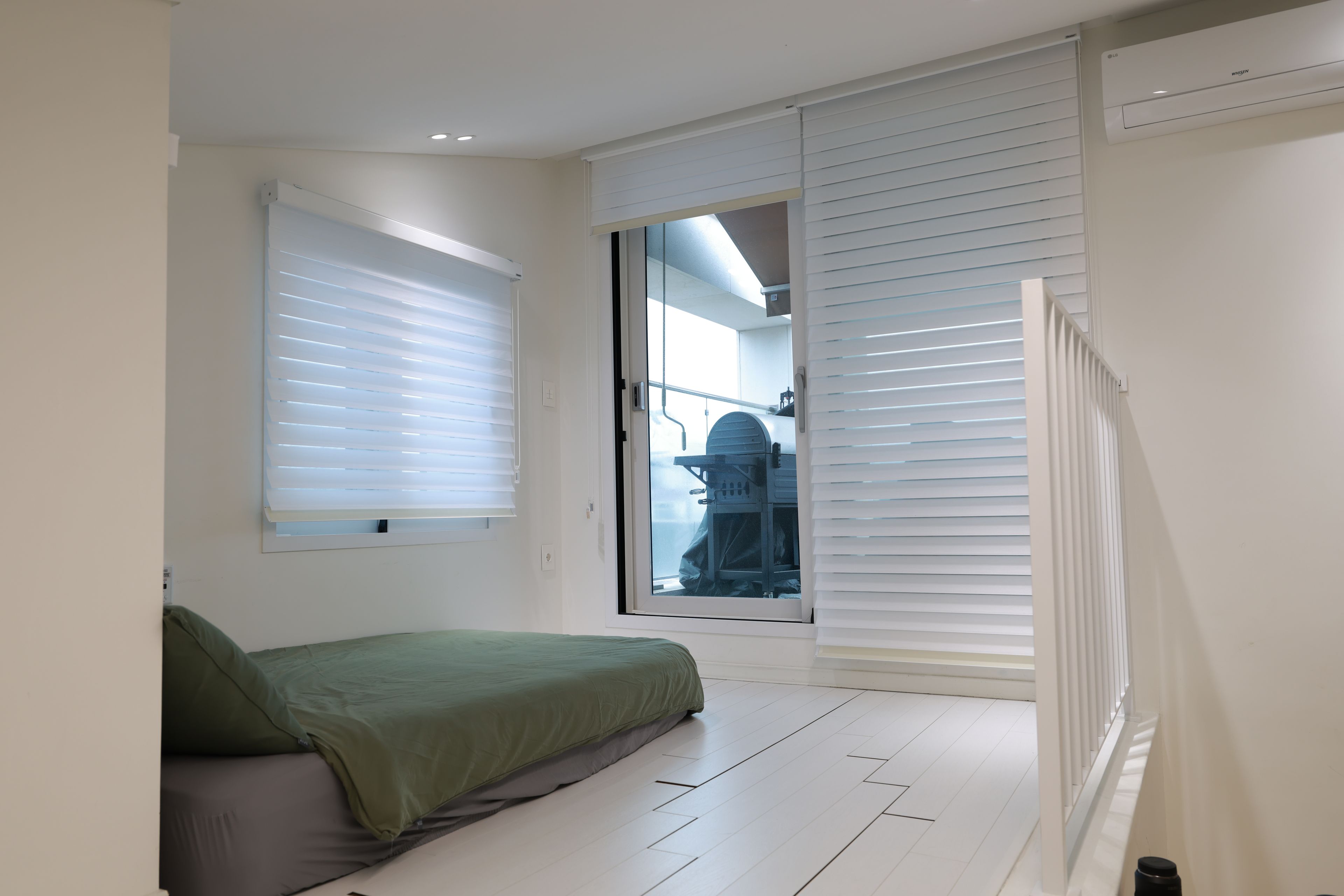 A bedroom with a bed, a window with blinds, a radiator, and a door leading to a balcony.