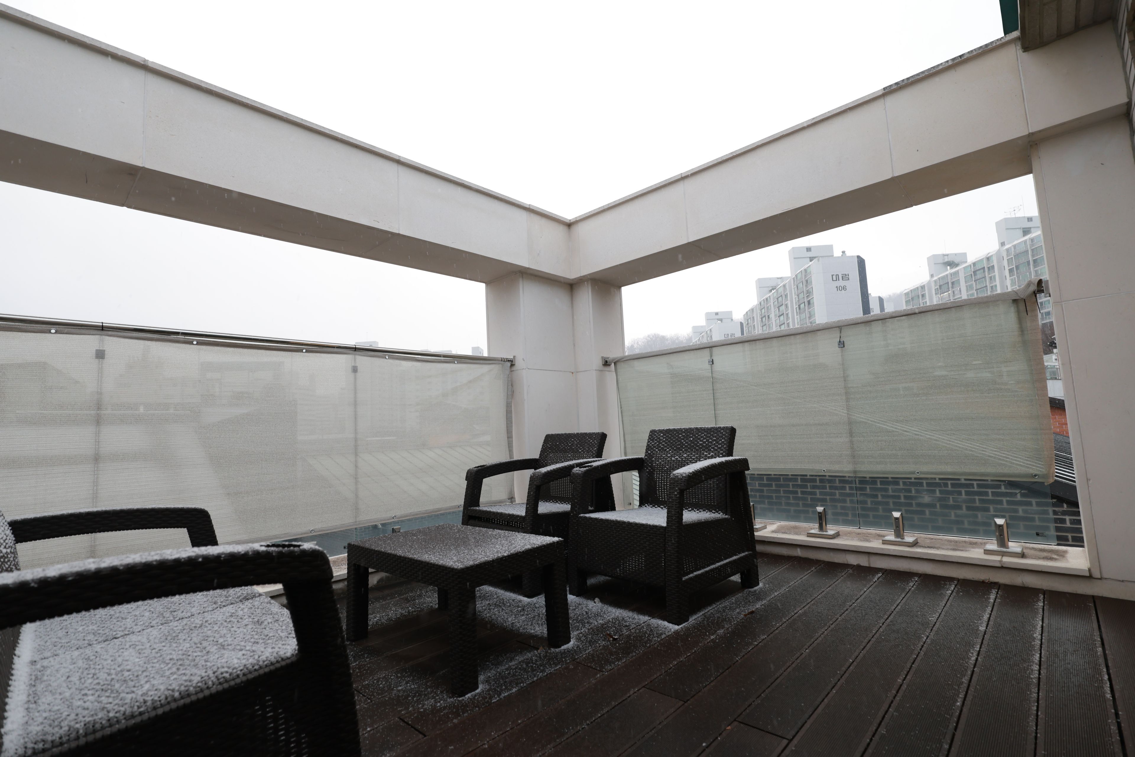 A rooftop terrace with a seating area, a view of the cityscape, and a glass balustrade.