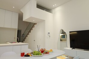 A modern kitchen with a dining area, a staircase, and a flat-screen TV. - Seocho/Gangnam - Charming Family Home - 3-Story-Home - 15 Guests - 3BR/3BTH (Seoul)
