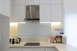 A modern kitchen with white cabinets, a stainless steel range hood, a kettle, and a coffee maker. - Seocho/Gangnam - Charming Family Home - 3-Story-Home - 15 Guests - 3BR/3BTH (Seoul)