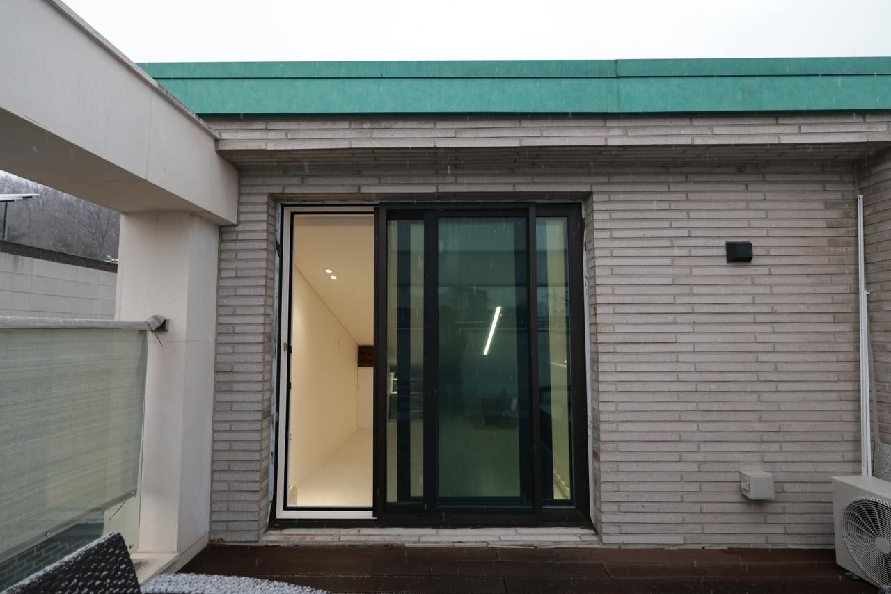 Un edificio con techo verde, puerta de cristal y pared de ladrillo.