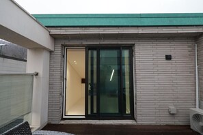 Un edificio con techo verde, puerta de cristal y pared de ladrillo.