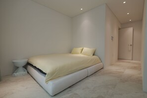 Un dormitorio moderno con una cama, una mesita de noche y una puerta.