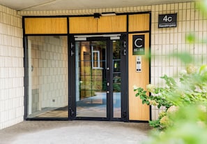 A building entrance with a wooden facade, a glass door, and a sign indicating room numbers 55-85. - Kawaleryjska Homely Apartment (Poznań)