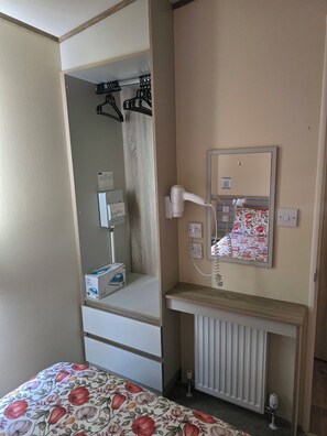 A hotel room with a bed, a vanity with a mirror, a radiator, and a hairdryer plugged in. - 3 bed- free parking, Deck and Chairs, Pet Friendly (Fleetwood blackpool)