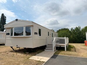 A mobile home with a front porch and a staircase leading to the entrance. - Cabin - Sleeps 8 - Hot Tub - Garden - Lake Side (Lincoln)