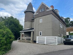 A two-story building with a conical tower, a gated driveway, and a parked vehicle. - 2 Apts • 3 Private Parking Spaces • Near CMU/Pitt (Pittsburgh)