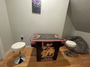Ein kleiner Automatenstand mit zwei Hocker, einem Plüschtier und einem an der Wand hängenden Bild.
